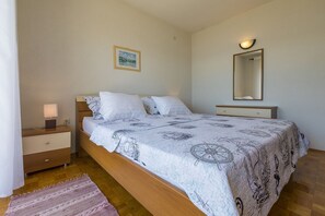 Ein Schlafzimmer mit einem Bett, einem Nachttisch, einer Lampe und einem Spiegel.