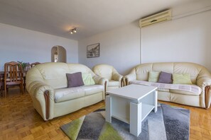Ein Wohnzimmer mit zwei hellbeigen Sofas, einem weißen Couchtisch und einem Holzessttisch mit Stühlen.