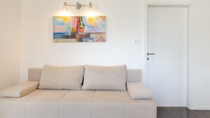 Ein sofas in neutralen Farben mit Kissen, ein abstraktes Wandbild und eine weiße Tür.