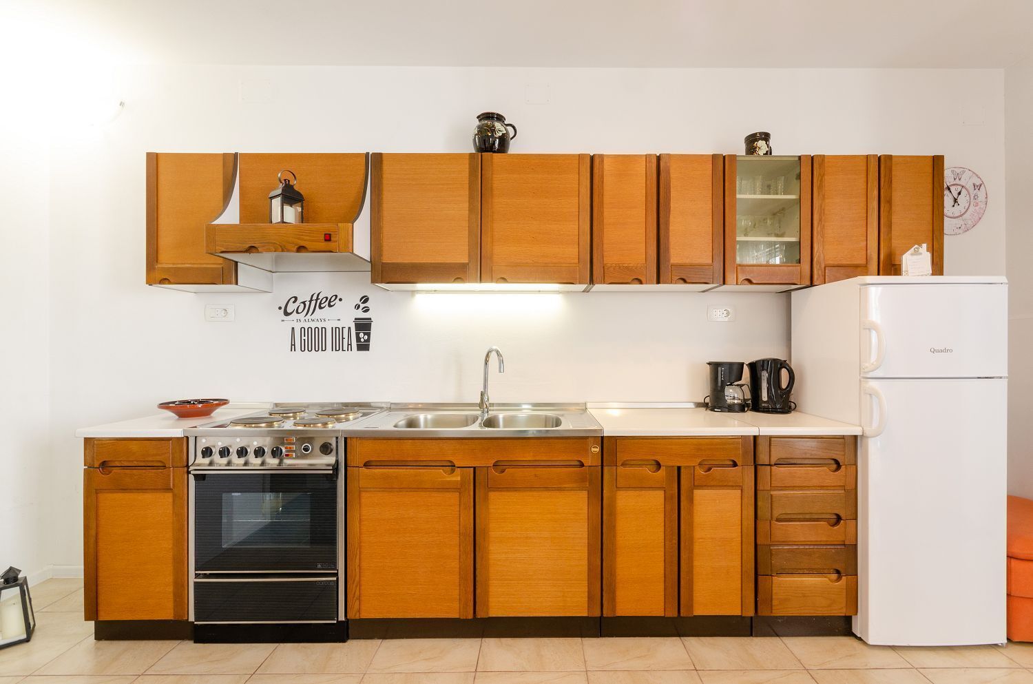 Una cocina con armarios de madera, estufa, fregadero y refrigerador.