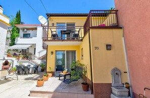 A yellow building with a balcony, outdoor seating, and potted plants. - Comfortable apartment just 300 metres from the beach with sea view, deckchair, barbecue (Crikvenica)