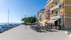 Eine Uferpromenade mit Außenbestuhlung und Blick auf das Meer.