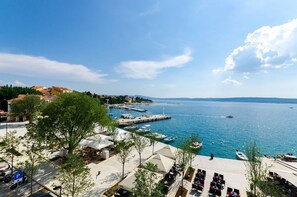 Een kustgezicht met een jachthaven, terras en helderblauwe lucht.