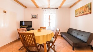 A dining area with a round table, wooden chairs, a sofa, a television, and a painting on the wall. - The perfect starting point for outdoor fun in Kvarner Bay (Bribir)