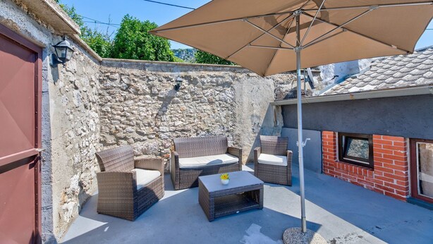 A patio area with wicker furniture, a table, and a large umbrella. - The perfect starting point for outdoor fun in Kvarner Bay (Bribir)