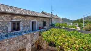 A stone building with a tiled roof, a small porch, and a garden with grapevines. - The perfect starting point for outdoor fun in Kvarner Bay (Bribir)