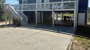 A two-story house with a covered patio, a staircase, and a fenced outdoor area. - About Time!
 Creekside Coastal Retreat 4BR/3BA in Emerald Isle with golf cart (Emerald Isle)