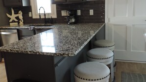 A kitchen with dark cabinets, a granite countertop, a coffee maker, and a sink. - About Time!
 Creekside Coastal Retreat 4BR/3BA in Emerald Isle with golf cart (Emerald Isle)