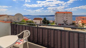 Un balcone con tavolo e sedie, vista su un corpo d'acqua e edifici.