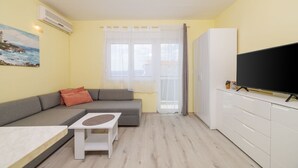 Un ambiente compatto con un divano, un tavolino, una TV e un mobile.