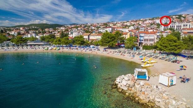 Una cittadina costiera con una spiaggia, acque cristalline e edifici sullo sfondo.