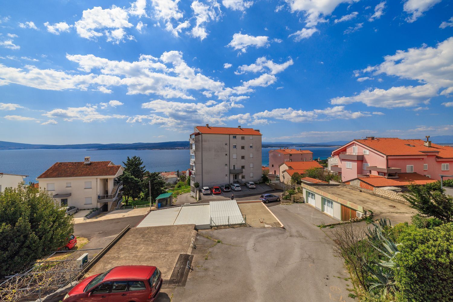 Un quartier résidentiel situé sur la côte, avec un grand immeuble, un parking et une vue sur la mer.