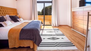 Ein Schlafzimmer mit einem Bett, einer Holzkommode, einem Deckenventilator und Blick durch eine Glastür.