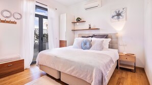 Ein Schlafzimmer mit Bett, Nachttischen, Fenster und Tür.