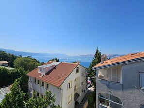 Ein Wohngebiet mit Gebäuden, blauem Himmel und Blick auf das Meer.