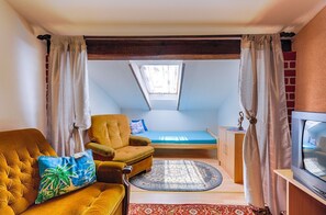 A small, cozy room with a loft bed, a sofa, a TV, and a window with curtains. - Vintage apartment just 490 metres from the beach with sea views, barbecue area, air conditioning (Dramalj)