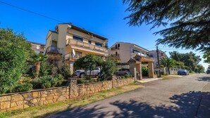 Una calle residencial con casas, muros de piedra y coches aparcados.