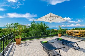 A rooftop terrace with two lounge chairs, a large umbrella, and potted plants. - Mediterranean apartment with sea view, parking space, cot, garden (Crikvenica)