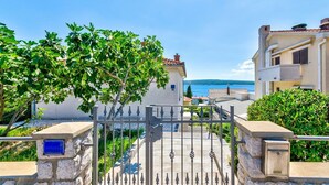 A gated entrance to a coastal property with a clear view of the sea and mountains in the background. - Bright apartment just 200 metres from the sandy beach with sea views (Crikvenica)