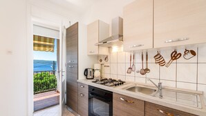 A modern kitchen with a view of the sea, a coffee machine, and a stove. - Bright apartment just 200 metres from the sandy beach with sea views (Crikvenica)