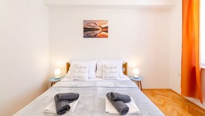 Un lit bien fait, avec deux oreillers, une table de chevet avec une lampe et un tableau accroché au mur.