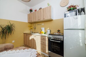 Eine kleine Küche mit Holzausstattung, einem Herd, einem Kühlschrank und einem Spülbecken.