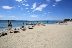 A beach with rows of sun loungers and umbrellas, a clear sky, and calm sea. - Vintage-style apartment just 70 metres from the beach with sea views and parking space (Crikvenica)