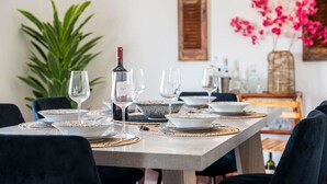 Mesa de jantar posta com pratos, copos e uma garrafa de vinho, rodeada de cadeiras.