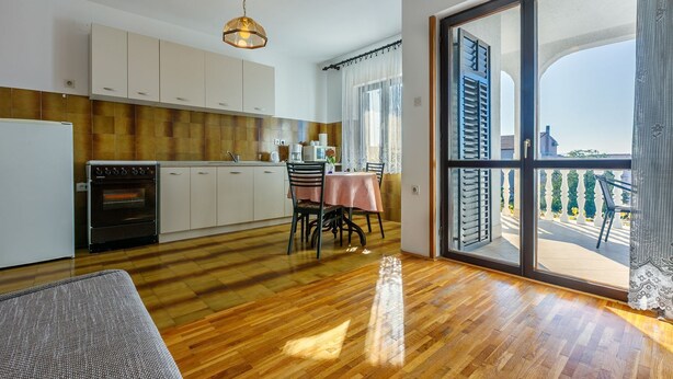 Una cucina moderna con zona pranzo e un'ampia porta-finestra scorrevole che dà su un balcone.