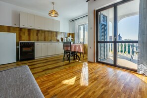 A modern kitchen with a dining area and a large sliding glass door leading to a balcony. - Charming flat with sea view, private parking, garden and barbecue (Crikvenica)