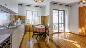 Una cucina moderna con zona pranzo, pavimento in legno e ampie finestre.