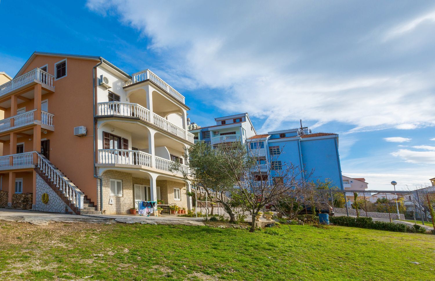 Un edificio residencial de varios pisos con balcones, una escalera y un césped.