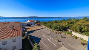 Ett bostadsområde vid kusten med byggnader som har tak av terrakotta, en parkeringsplats och utsikt över havet.