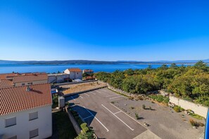Ein Küstenwohngebiet mit Häusern mit Terrakotta-Dächern, einem Parkplatz und Blick auf das Meer.