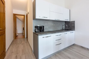 Eine moderne Küche mit weißen Schränken, einer grauen Arbeitsplatte und einer Kaffeemaschine.