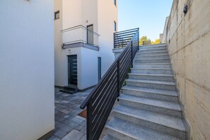 Eine Treppe mit Metallgeländer führt zu einer Tür mit Glasschiebeelement.