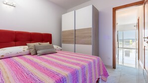 A bedroom with a bed, a red headboard, a wardrobe, and a balcony with a view. - Light-filled apartment with barbecue area, sea view, washing machine (Crikvenica)