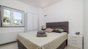 A bedroom with a bed, a nightstand, a window, and a view of the outside. - Fascinating apartment with barbecue area, sea view, parking space, washing machine (Crikvenica)