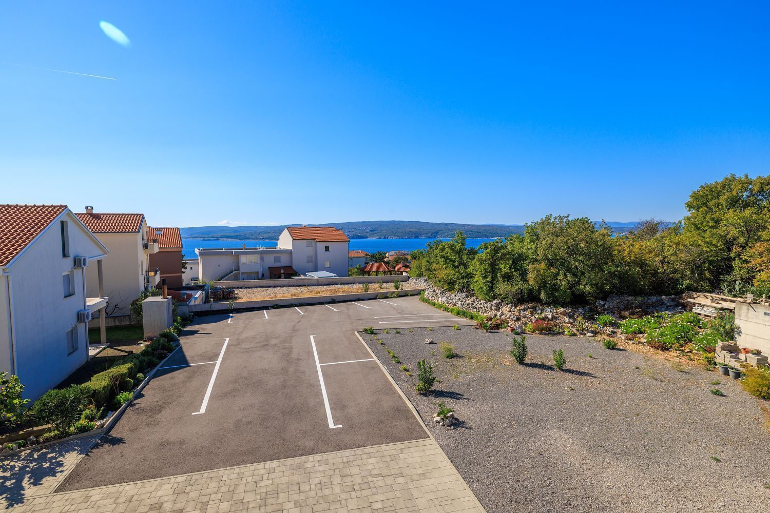 A parking lot with a view of a coastal area, including buildings and trees.