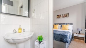 Un baño moderno con un lavabo blanco, espejo y una planta pequeña en maceta.