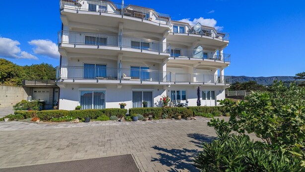 Un hotel de varios pisos con balcones, un patio empedrado y abundante vegetación.