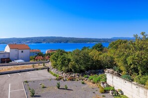 A coastal residential area with a parking lot, a small building with a red roof, and a view of the sea and distant hills. - Unique studio apartment with picturesque sea views (Crikvenica)