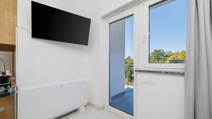 Una cocina moderna con estufa integrada, televisor de pantalla plana y puerta corrediza de vidrio que da a un balcón.
