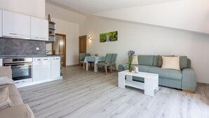 Un appartement moderne comprenant une cuisine, un coin repas et un salon. Il est équipé d’un canapé, d’une table basse et d’une table à manger avec des chaises.