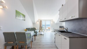 Une cuisine moderne avec un coin repas, comprenant une table avec des chaises, un canapé et une vue sur la mer grâce à une grande fenêtre.