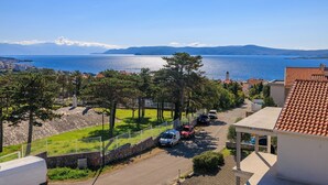 Ett bostadsområde vid kusten med fri utsikt över havet, en stenmur och parkerade bilar.