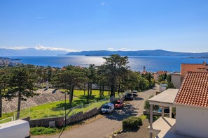 Un quartier résidentiel situé sur la côte, offrant une vue dégagée sur la mer, avec un mur de pierre et des voitures garées.