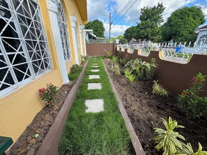 Ein Weg, der von einem Garten mit verschiedenen Pflanzen und einem Zierzaun gesäumt wird.