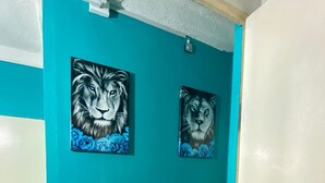 Un pasillo con paredes verde azuladas y dos cuadros con imágenes de leones.