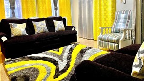 Una sala de estar con un sofá marrón oscuro, un sillón a rayas y una alfombra estampada.